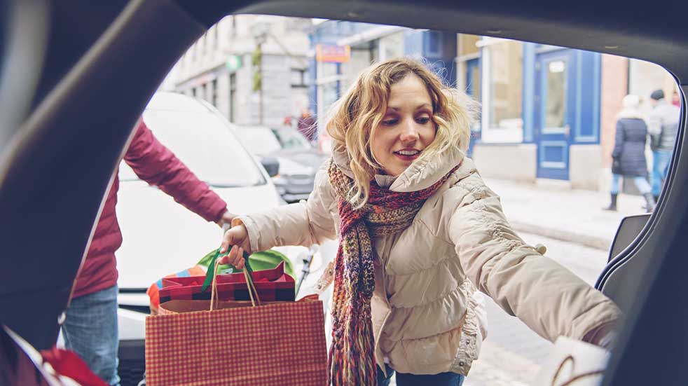 Winter driving woman putting Christmas shopping in car